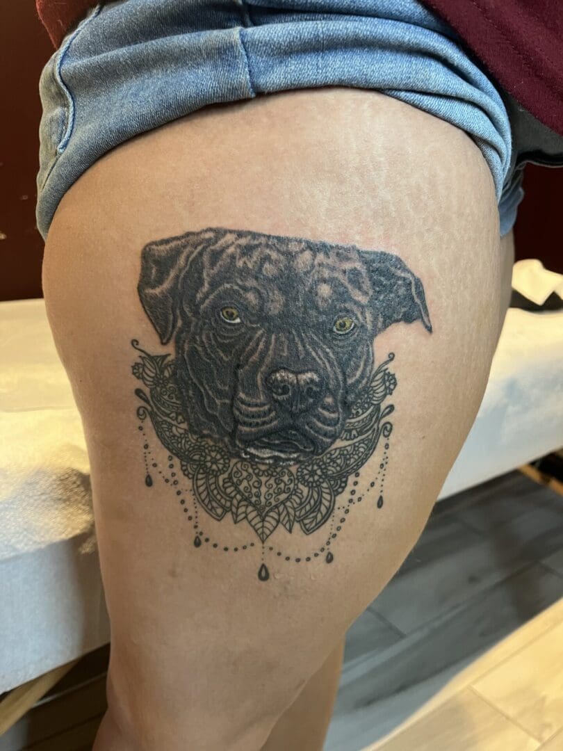 A tattoo of a dog 's face on the side of a leg.