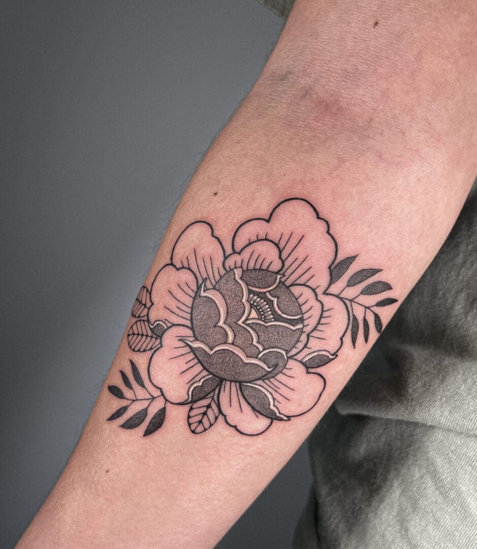 A black and white flower tattoo on the arm of someone.