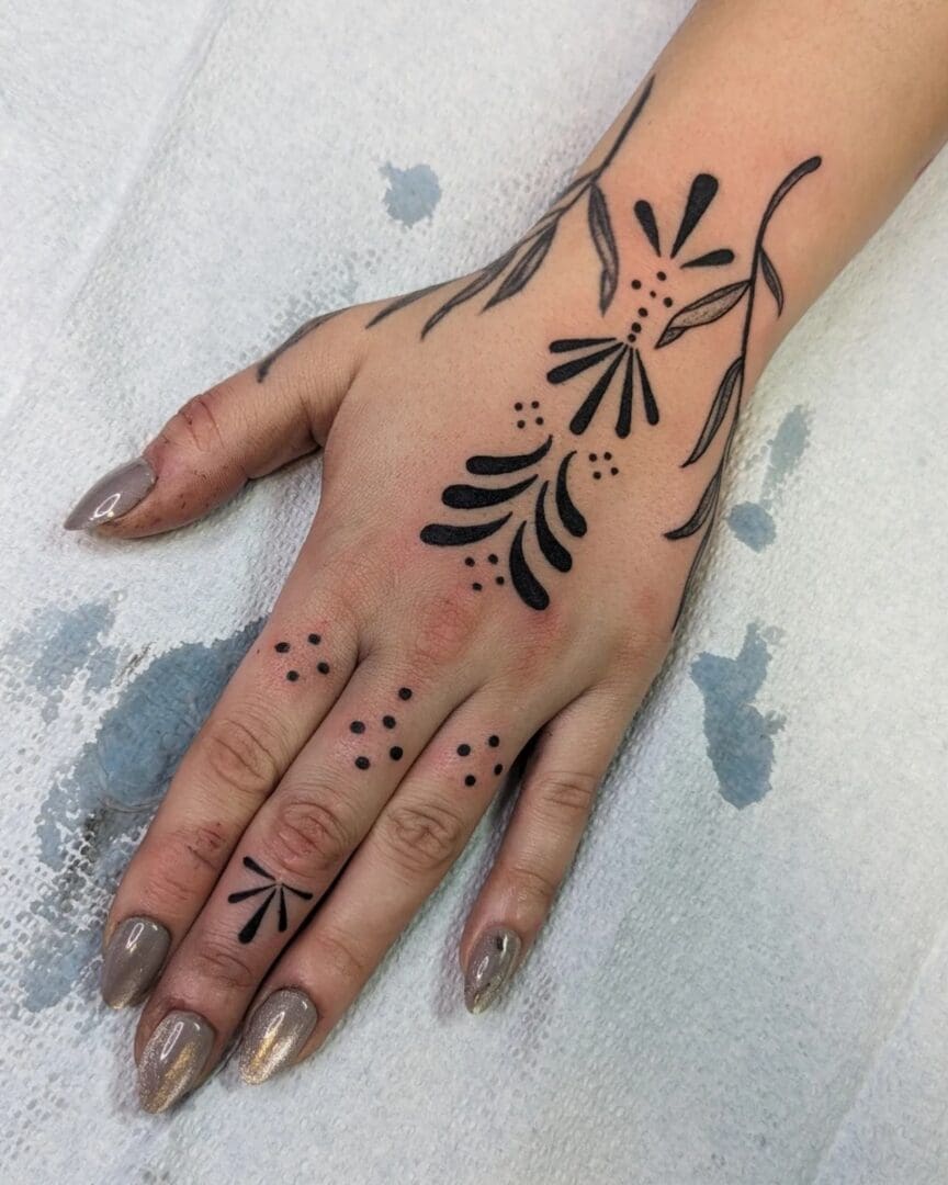 A woman 's hand with black and orange designs on it.
