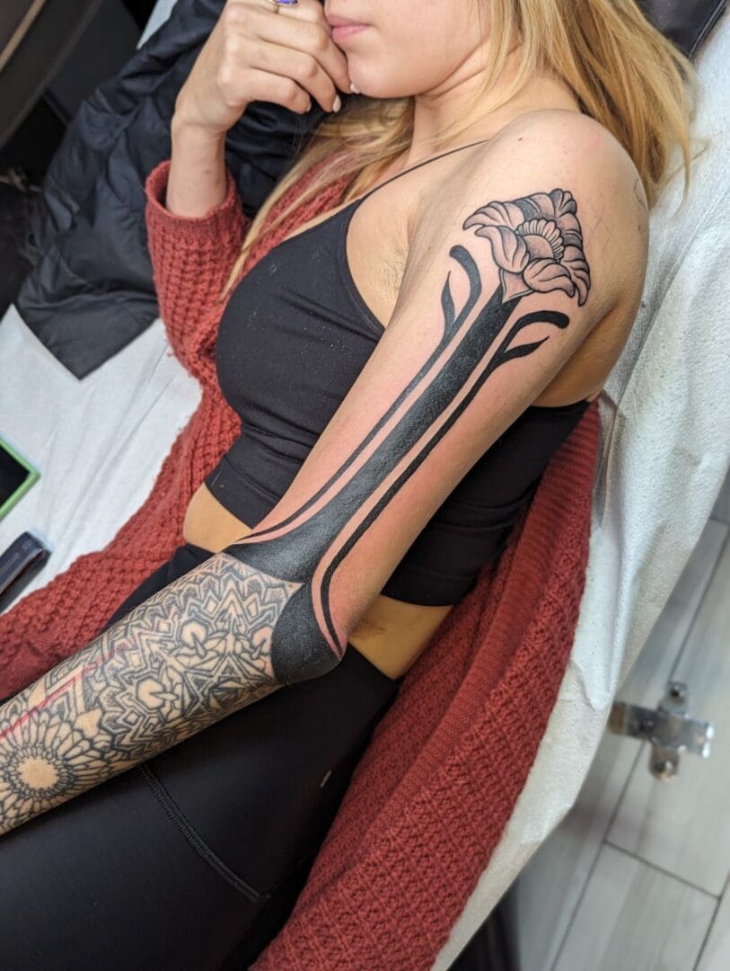 A woman sitting on the couch with her arm in a tattoo.